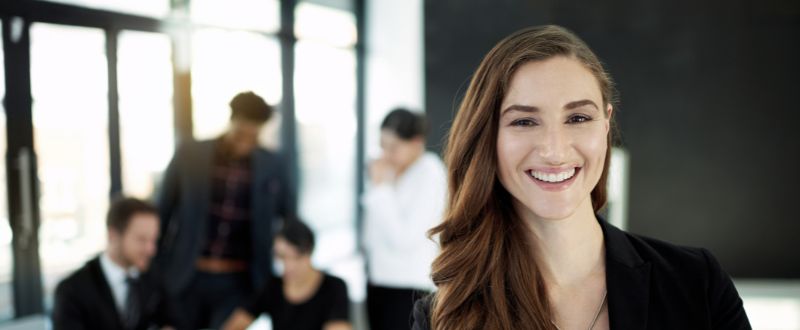 a smiling business professional with a team in the background
